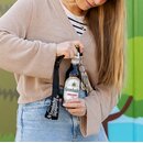 Eine Frau öffnet ihre Krombacher Flasche mit dem Flaschenöffner am Schlüsselband.