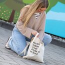 Frau kniet auf Pflastersteinen und hält einen Jutebeutel mit dem Text 'bitte nicht schubsen ich hab Krombacher im Beutel'.