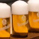 Drei Krombacher Probiergläser gefüllt mit Pils, auf Holzunterlage.