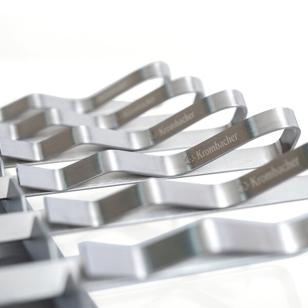 Mehrere silberne Schaschlikspieße aus Metall mit gewelltem Griff, auf denen das Wort 'Krombacher' eingraviert ist.