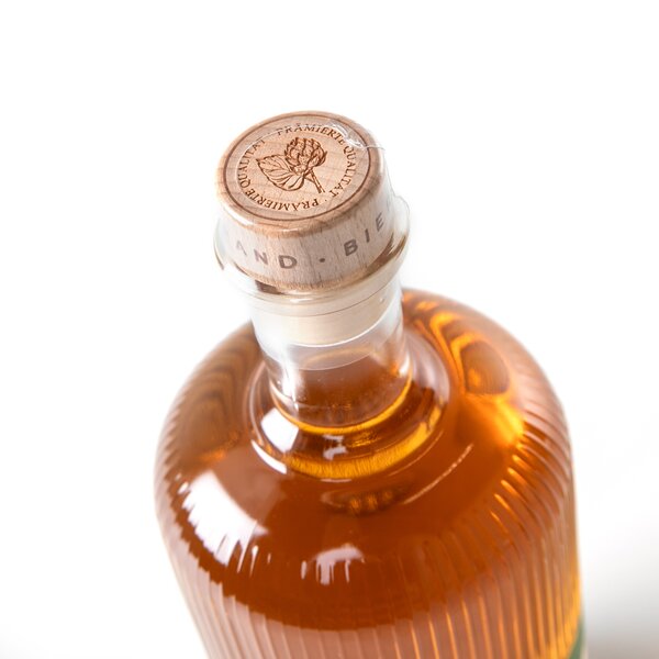 5554_krombachershop_Bierbrand_Der_Natu╠êrliche_Produkt_002 Flasche mit bernsteinfarbener Flüssigkeit, Holzverschluss mit Prägung.