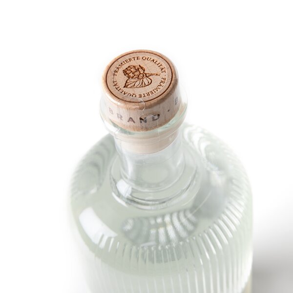 5552_krombachershop_Bierbrand_Der_Originale_Produkt_002 Flasche mit geriffeltem Glas und Holzverschluss, auf dem 'PRÄMIERTE QUALITÄT' eingraviert ist.