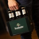 Hand hält einen dunkel grünen Krombacher-Sechserträger mit grüner Front und sechs Flaschen Krombacher Pils.