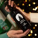 Zwei Hände halten eine braune Krombacher-Flasche mit weißem Druck, darauf ein stilisierter Weihnachtsbaum und der Text 'Fröhliche Weihnachten'.
