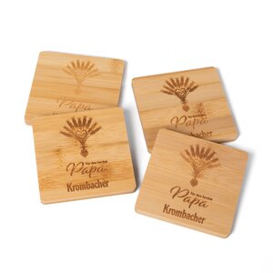 5559_KRO_UntersetzerPapa_9893_LR Vier Untersetzer aus Holz mit Gravur eines Weizenbündels und der Schrift 'Für den besten Papa Krombacher'.