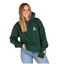 Frau trägt dunkelgrünen Hoodie mit kleinem Flaschendruck auf der Brust und Jeans, eine Hand in der Hosentasche