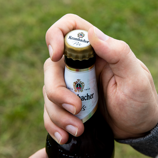 Hand hält eine Magnumflasche Krombacher Pils mit Gummiverschlusskorken.