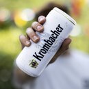Hand hält eine weiße Krombacher Bierdose mit Dosenkühler inklusive Krombacher Logo.